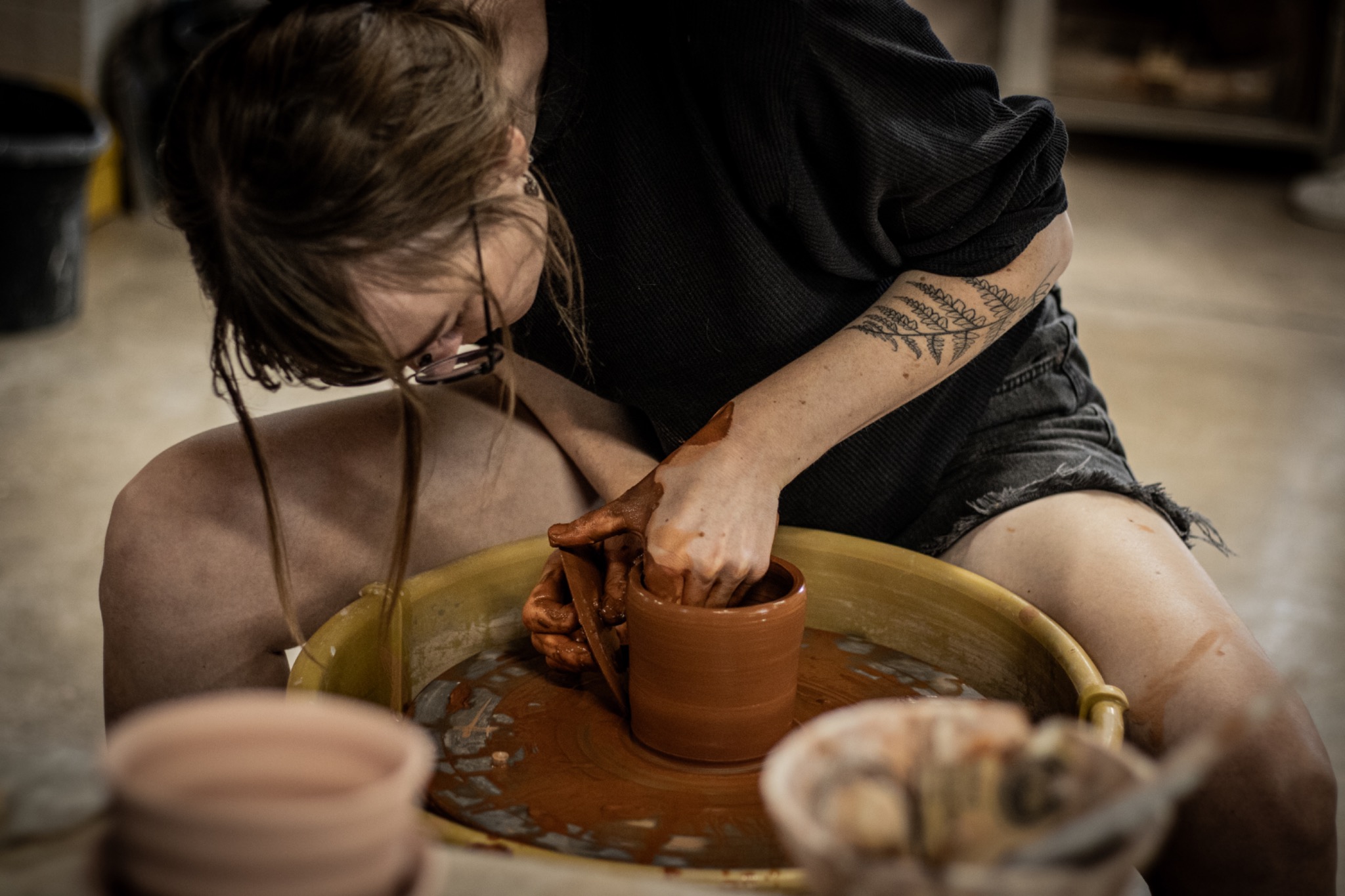 Two ceramic artists working together at a pottery wheel at Tucson Clay Co-op