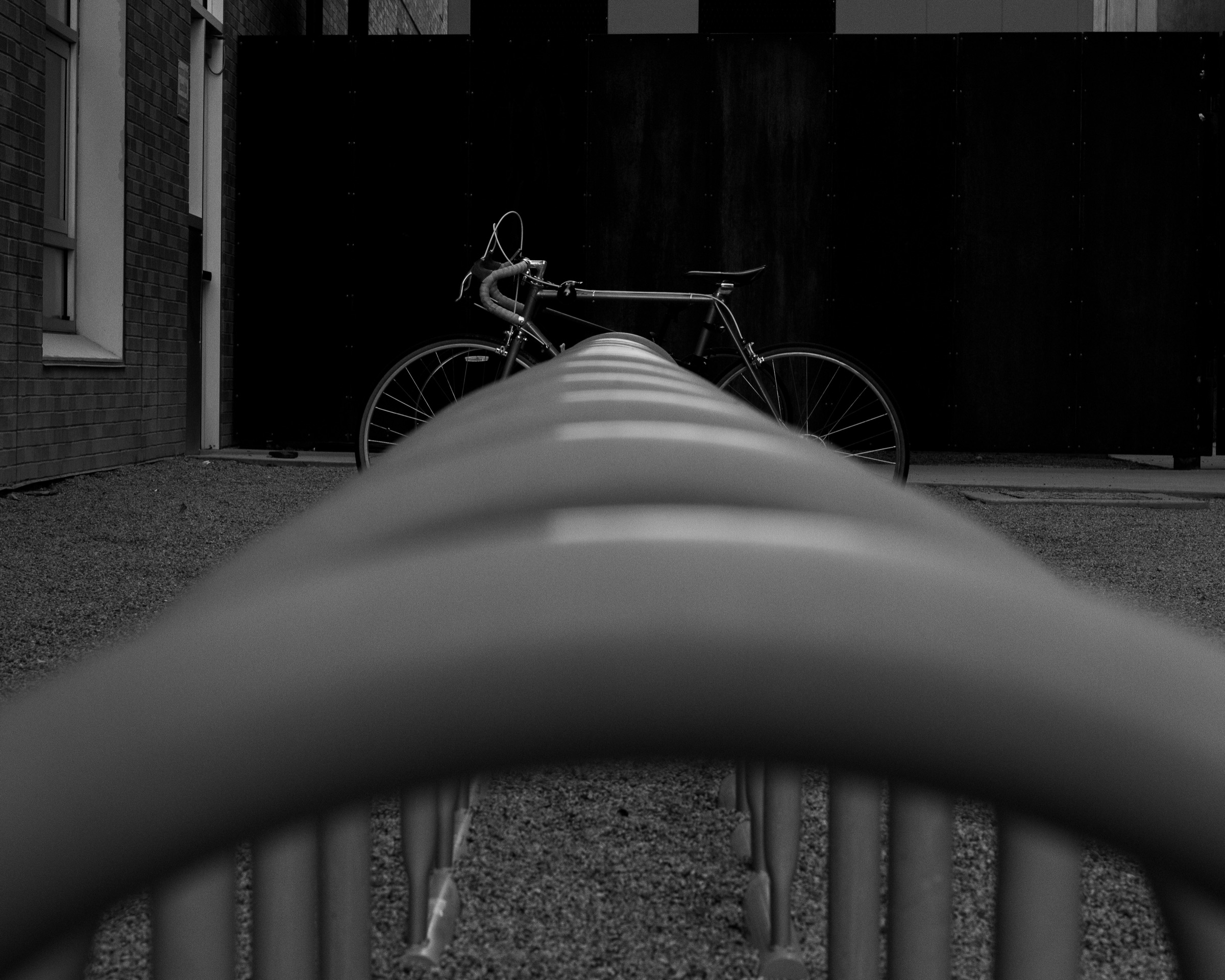 A curved foreground structure creates a visual path toward a bicycle